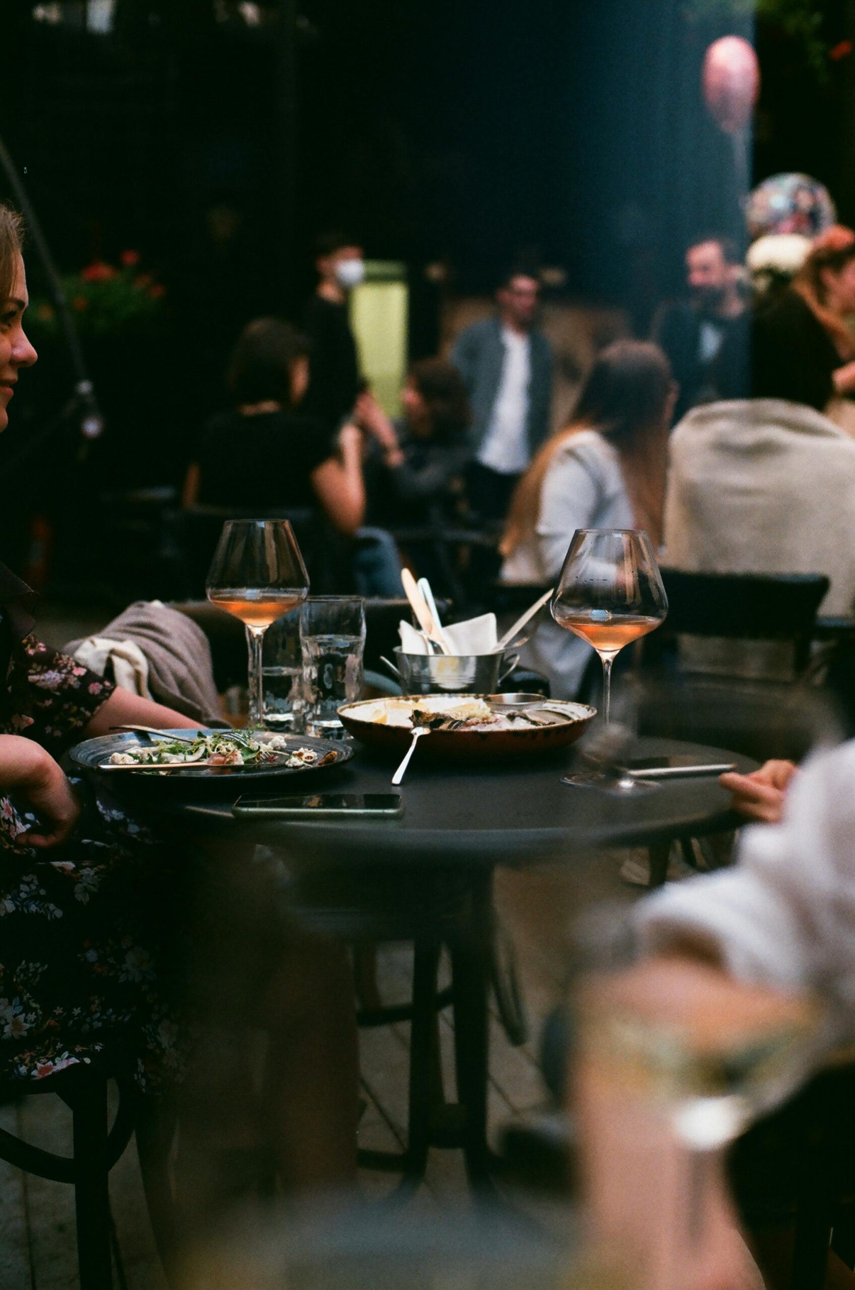 A bustling evening scene at a cozy restaurant with people dining and chatting.
